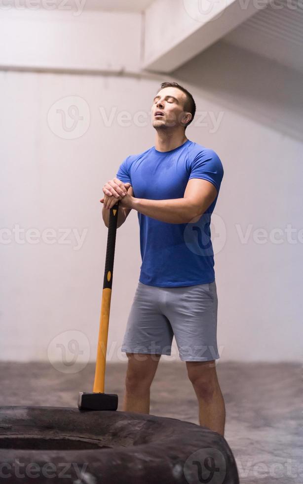 man workout with hammer and tractor tire photo