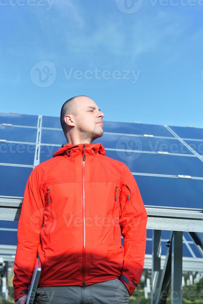 engineer using laptop at solar panels plant field photo