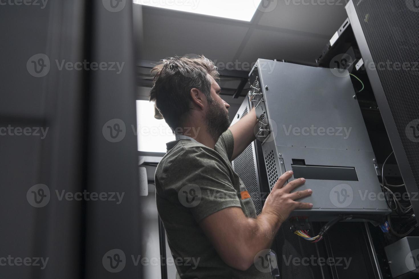 IT engineer working In the server room or data center The technician puts in a rack a new server of corporate business mainframe supercomputer or cryptocurrency mining farm. photo