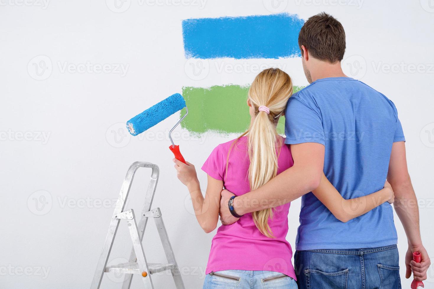 happy couple paint wall at new home photo