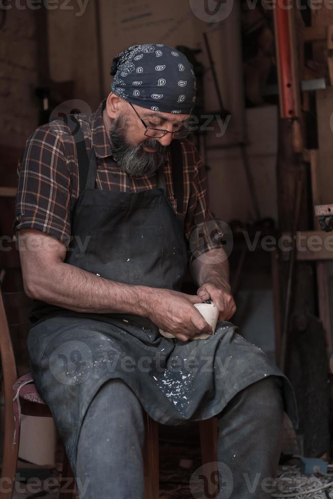 Spoon craft master in his workshop with handmade wooden products and tools working photo