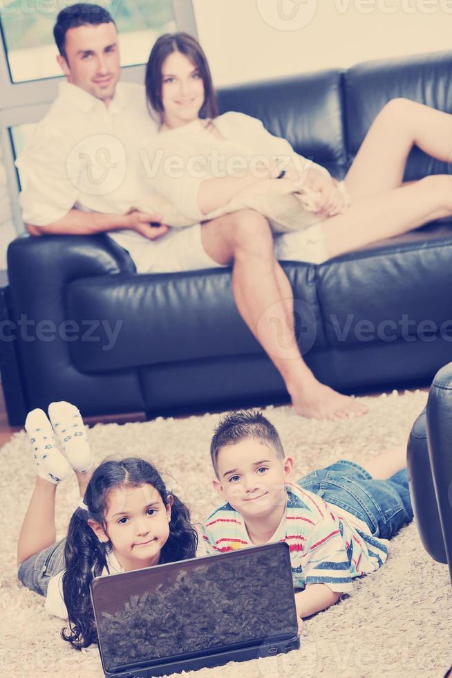 familia joven feliz divertirse y trabajar en la computadora portátil en casa foto