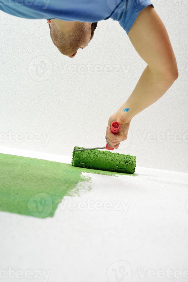 handsome young man paint white wall in color photo