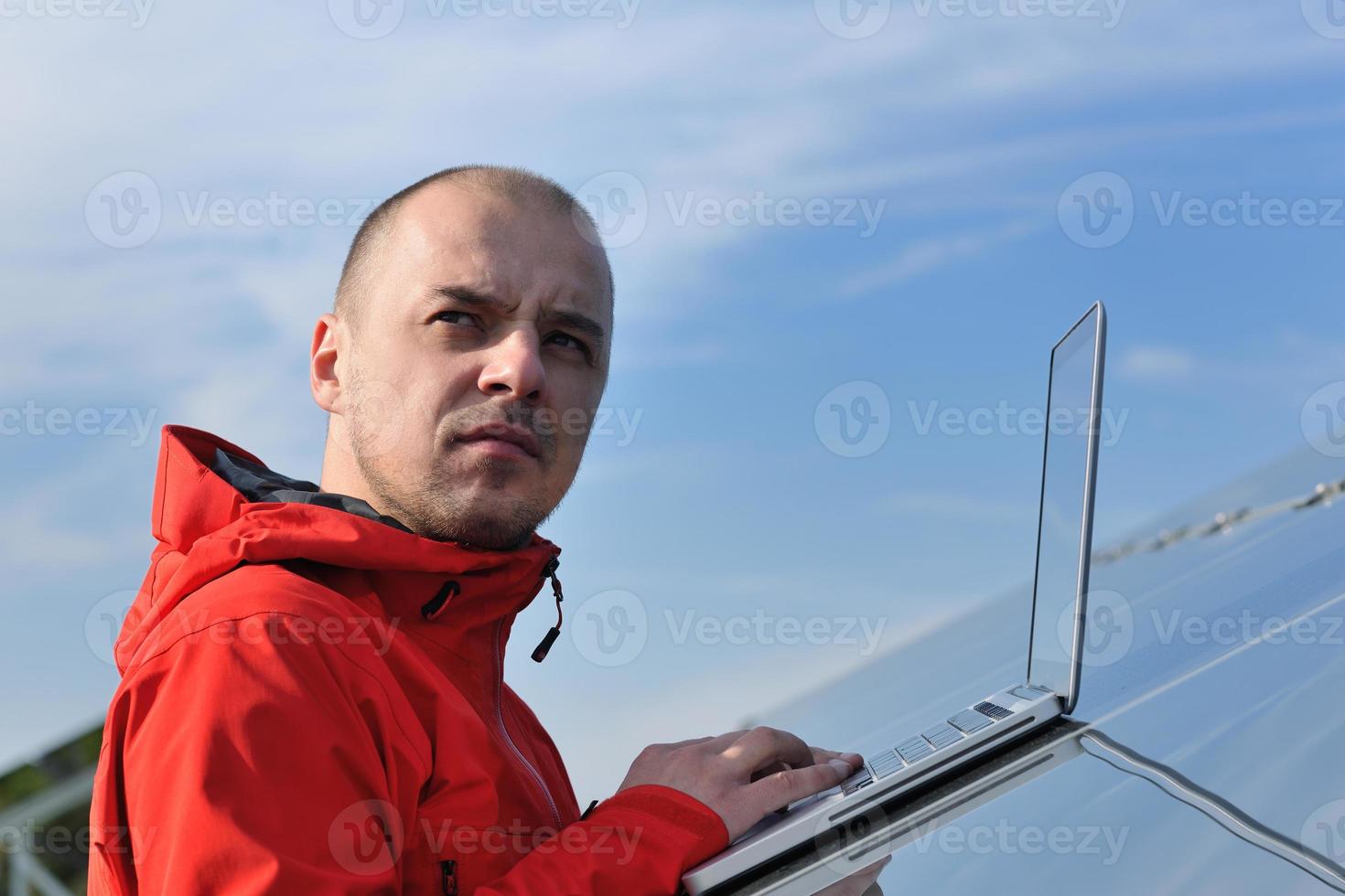 engineer using laptop at solar panels plant field photo
