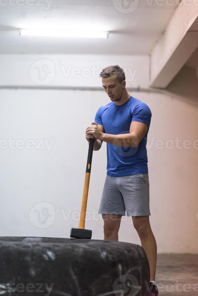 man workout with hammer and tractor tire photo