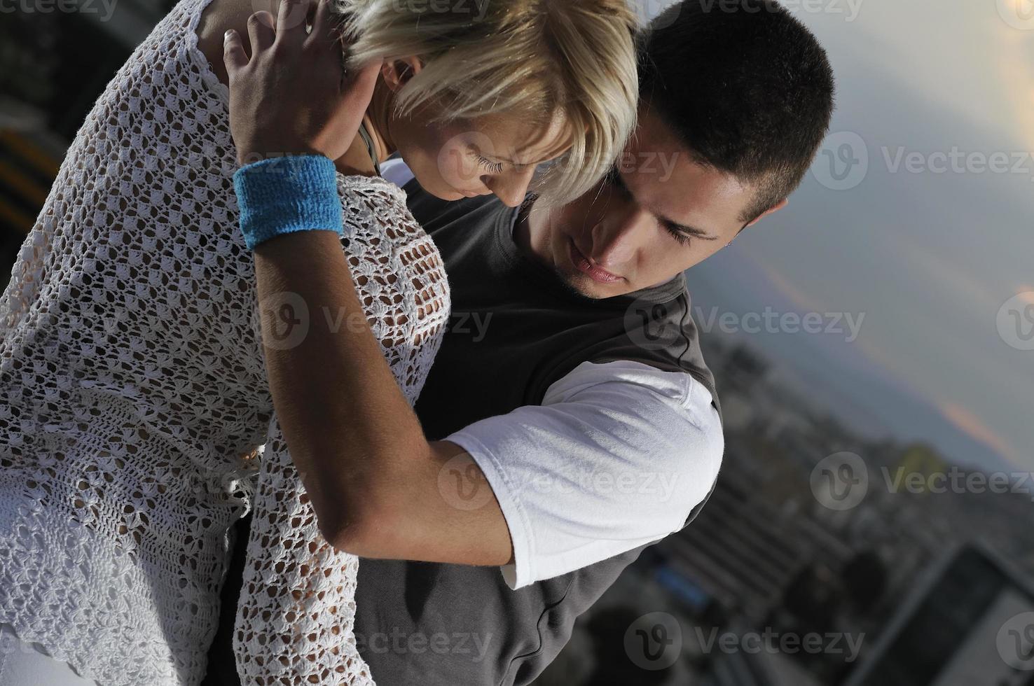 romantic urban couple dancing on top of the bulding photo