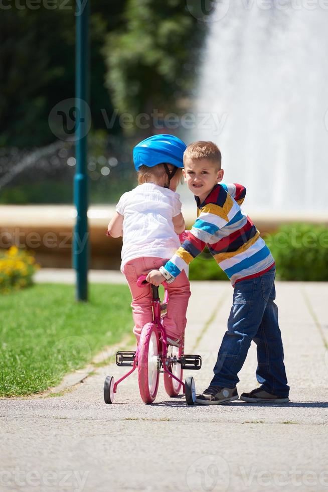 Boy and girl in park learning to ride a bike photo
