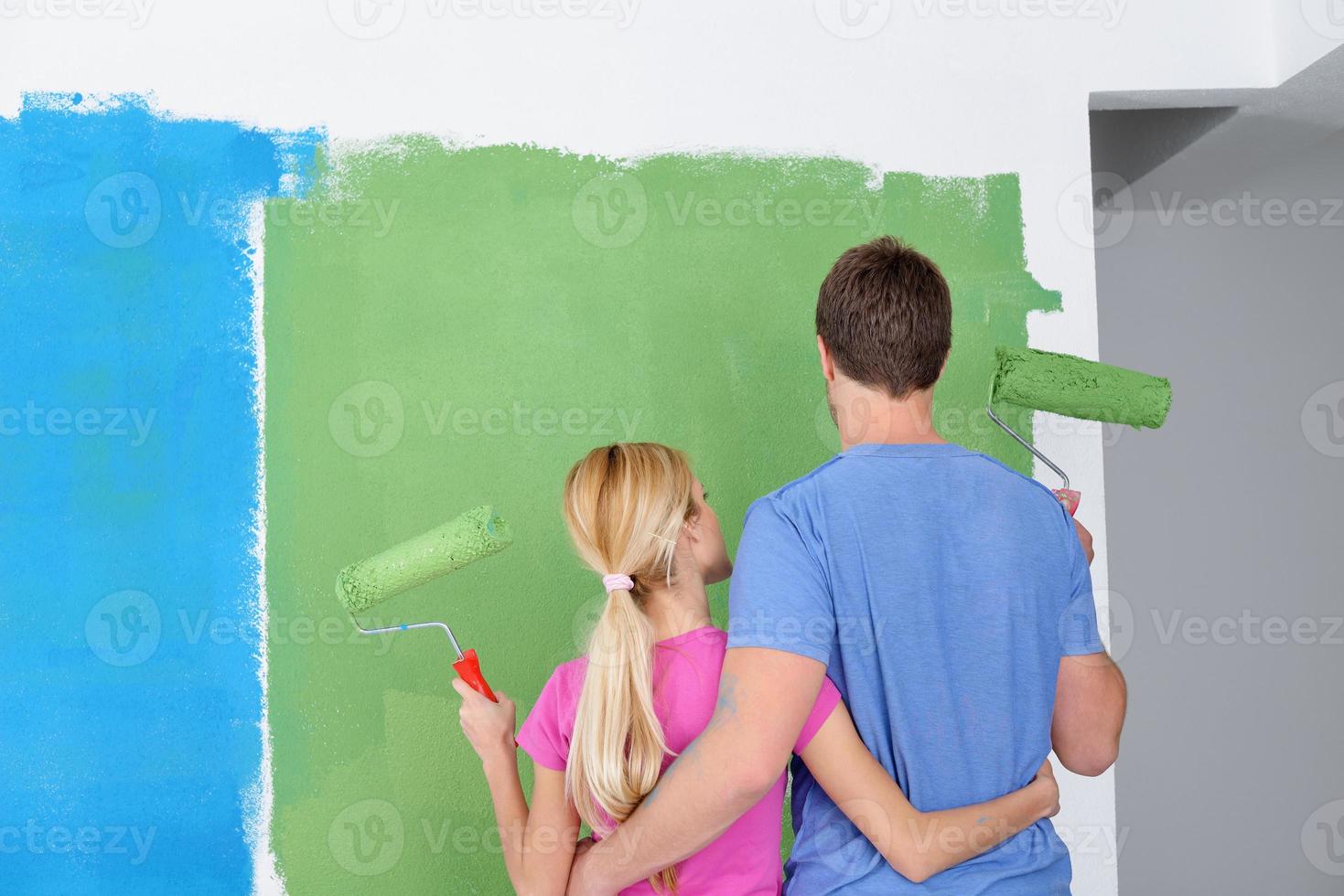 happy couple paint wall at new home photo