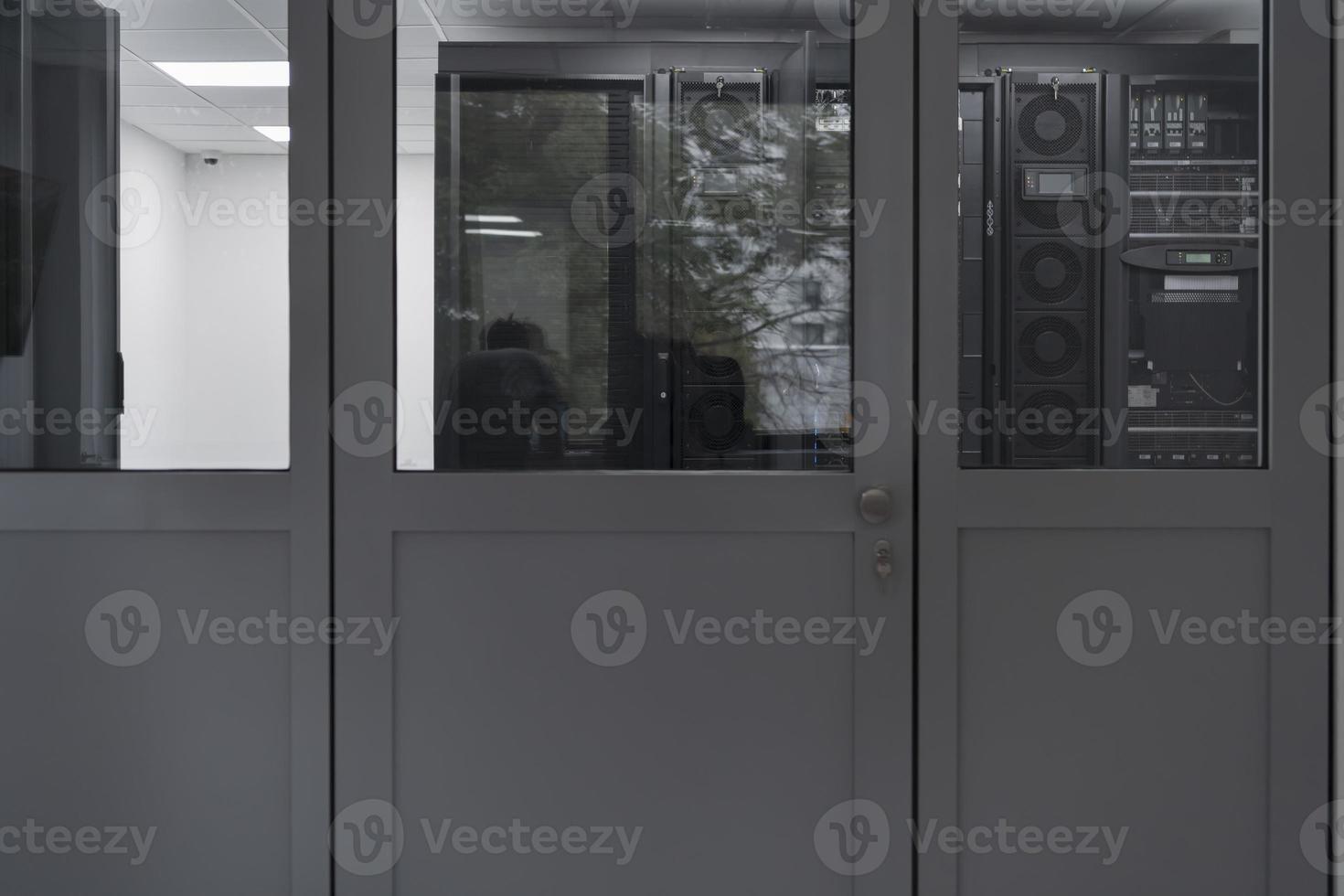 Software Engineer Working on a Laptop Computer in a Modern Server room. Monitoring Room Big Data Scientist in reflection of the entrance door. photo