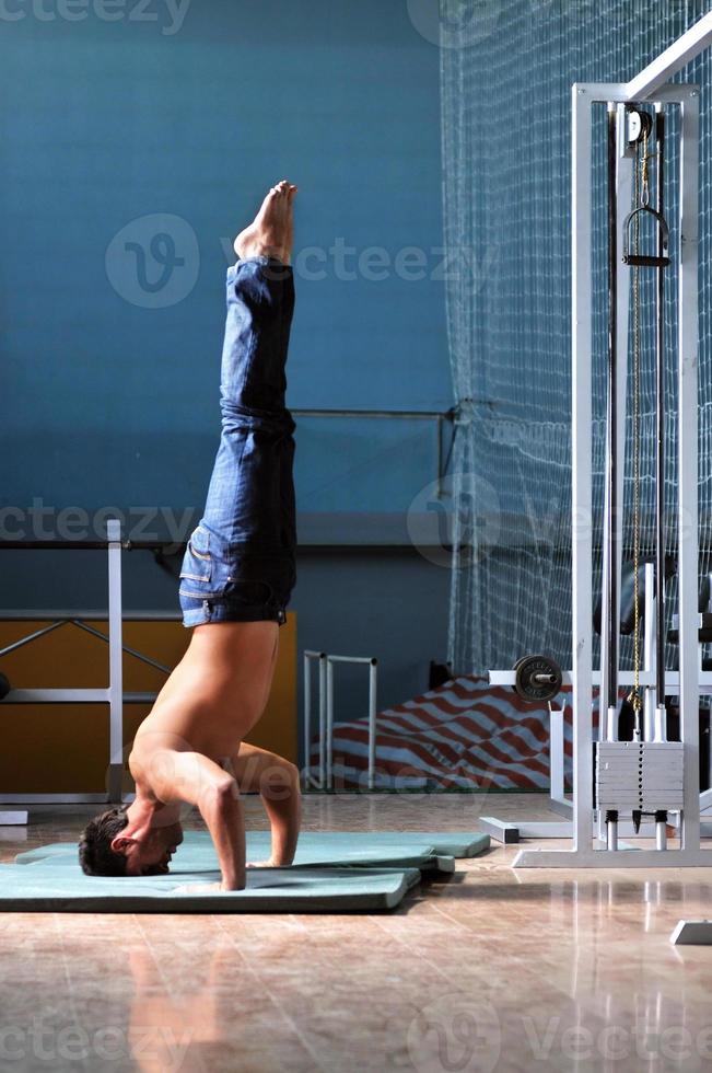 Young man performing  handstand in fitness studio photo