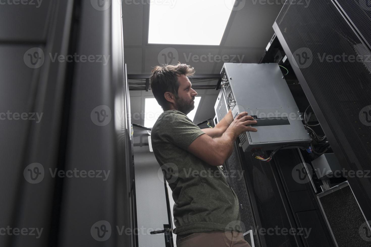 IT engineer working In the server room or data center The technician puts in a rack a new server of corporate business mainframe supercomputer or cryptocurrency mining farm. photo