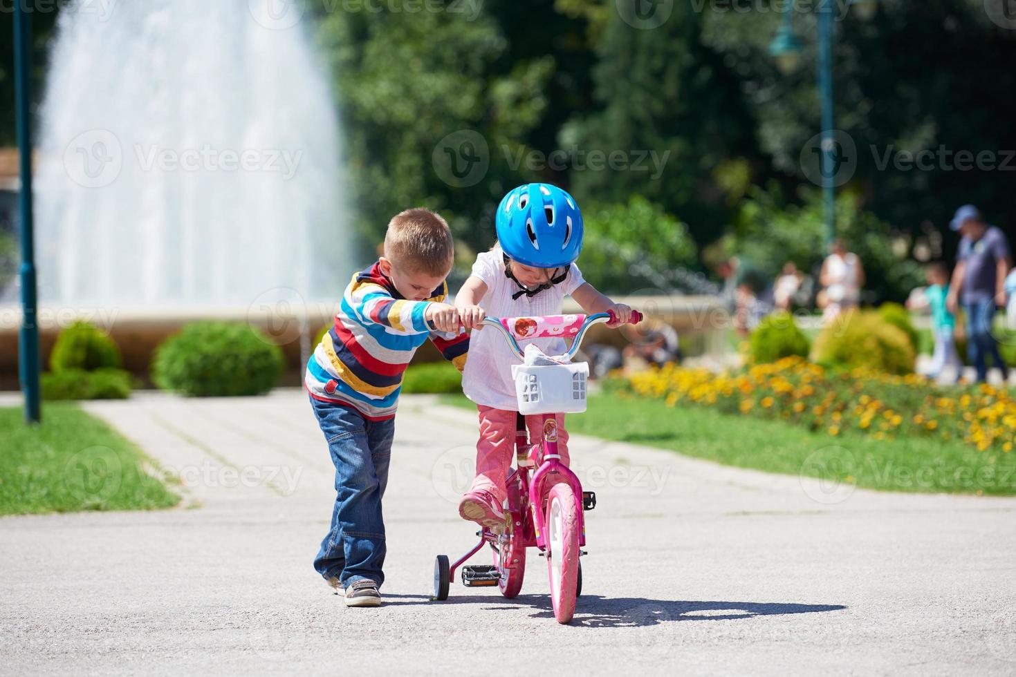 Boy and girl in park learning to ride a bike photo