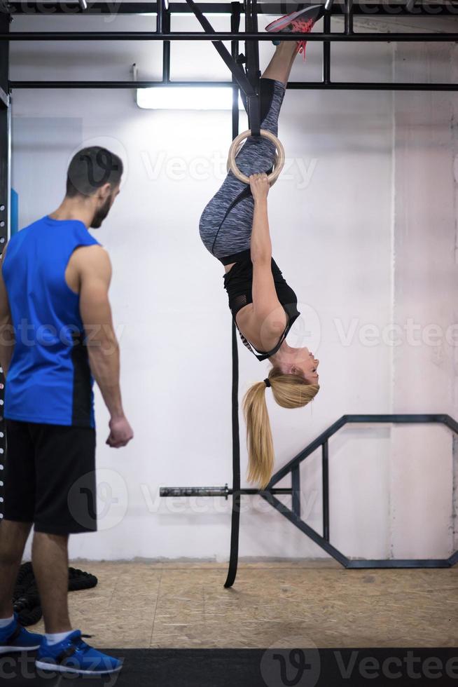 mujer trabajando con entrenador personal en anillos de gimnasia foto