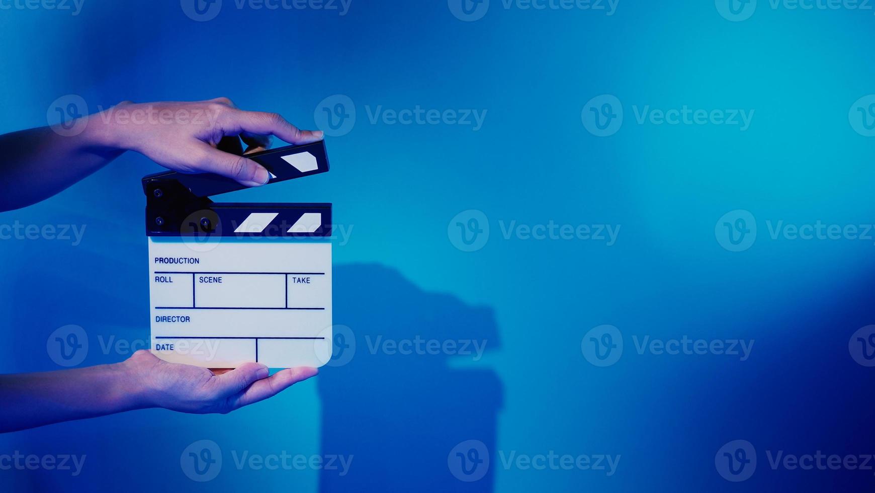 Crew hand holding plastic and wooden film slate board against camera. photo