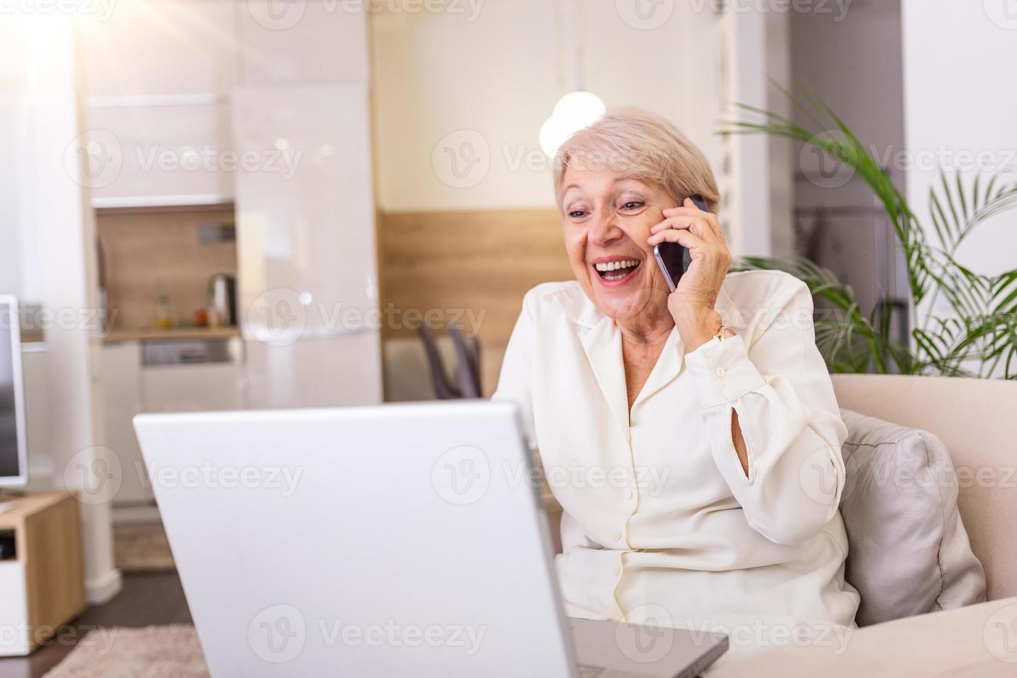 Senior woman receiving good news on phone. screaming out of happiness. Mature excited woman screaming in happiness while talking on a phone and using laptop photo