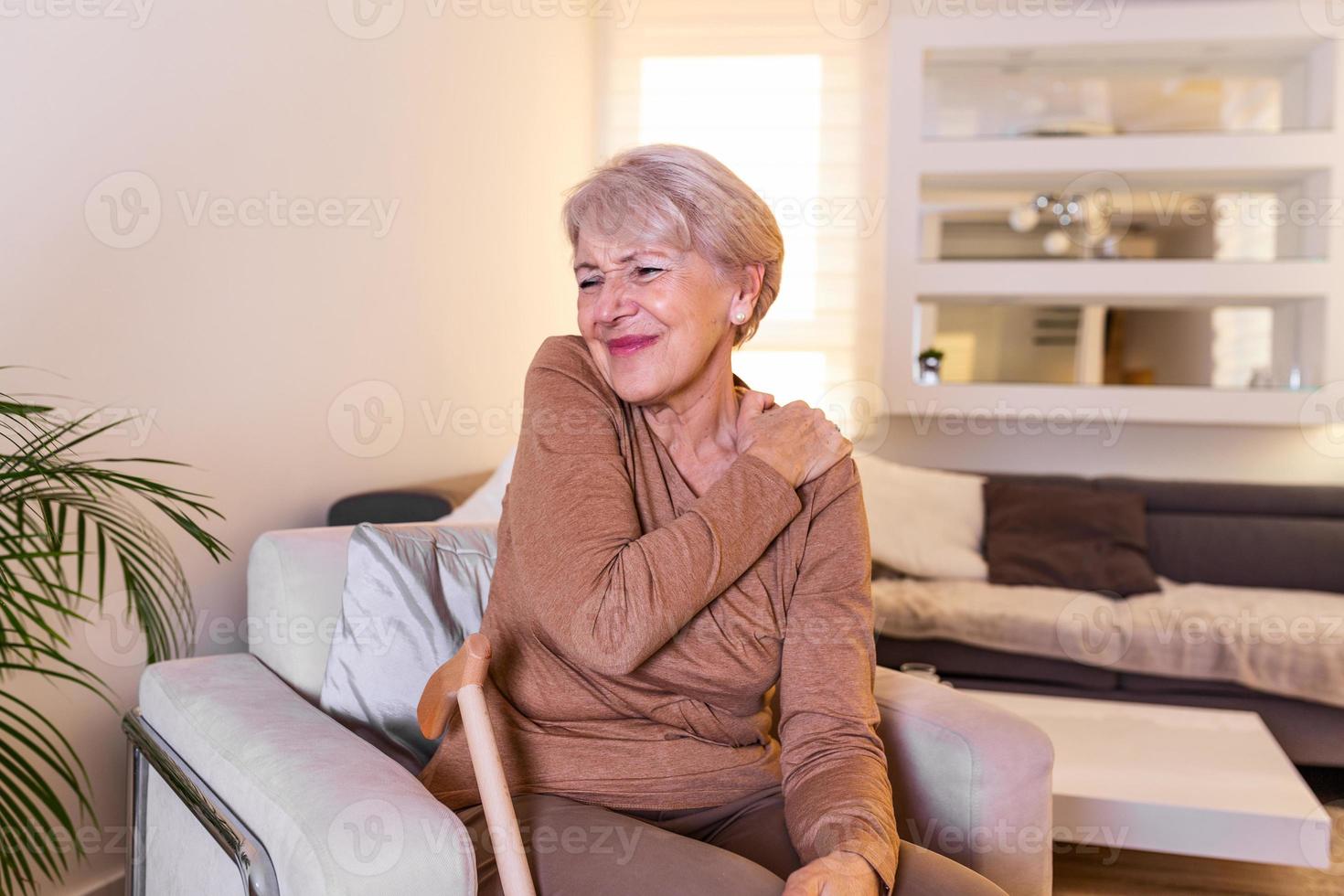 Elderly woman massaging the shoulder easing the aches. Joint pain concept. Senior old lady experiencing severe arthritis rheumatics pains, massaging, warming up arm. Close up, copy space, background photo