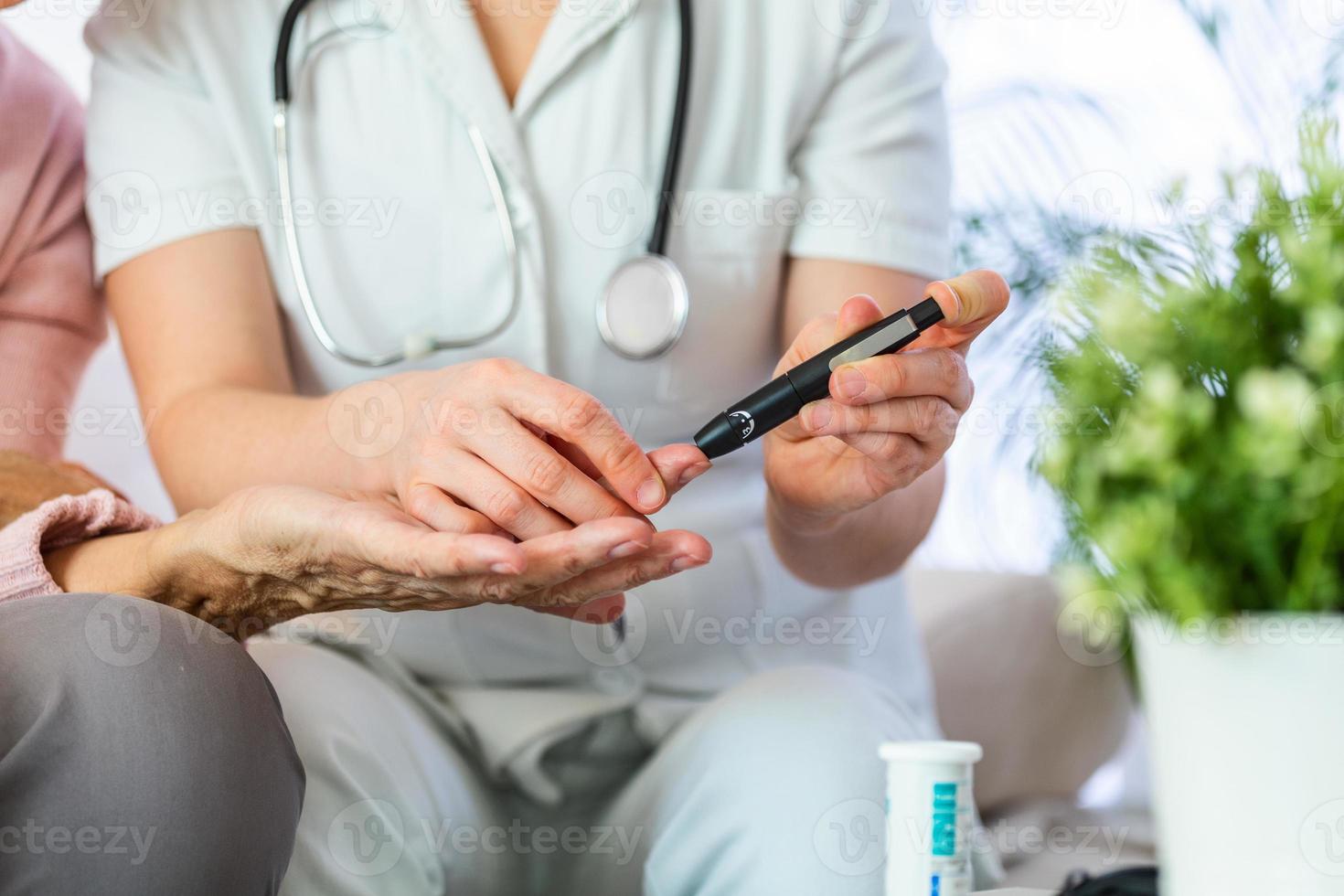 Nurse measuring blood sugar of senior woman at home. Young nurse measuring blood sugar of elderly woman at home. Doctor checking elderly woman's blood sugar - diabetes and glicemia concept photo