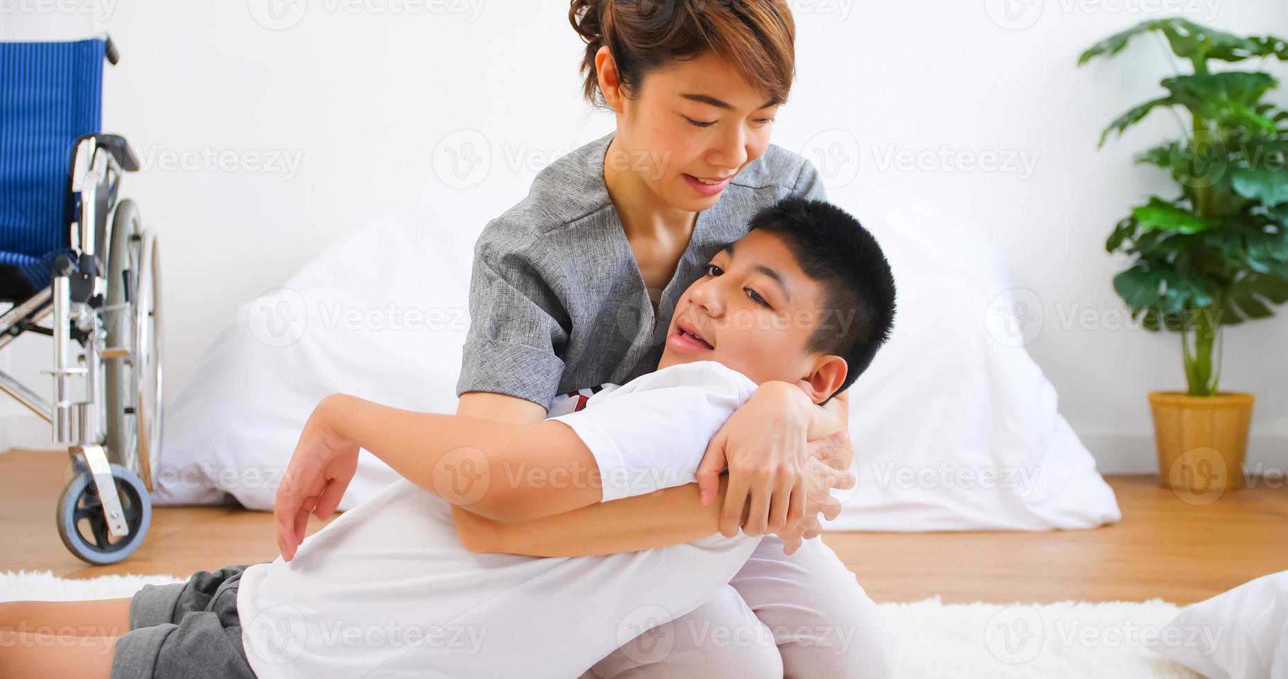 Disabled son has therapy by doing exercise with mother support and care. photo