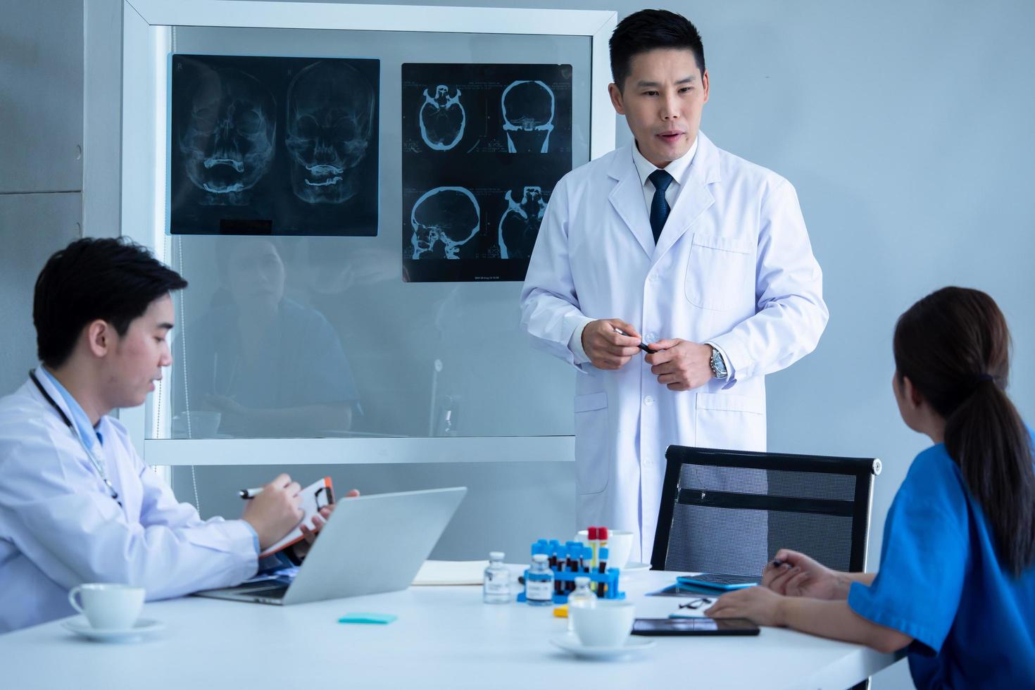 Doctor and medical assistants discussing about diagnosis result on x-ray film. photo