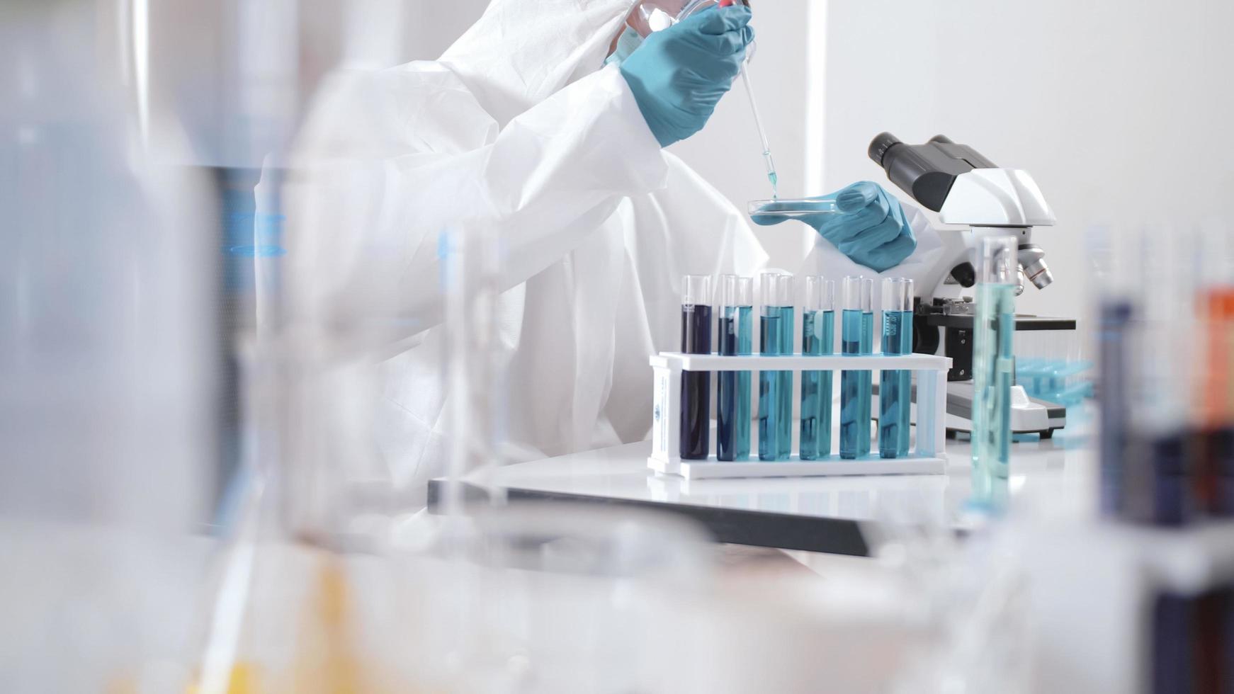 Scientist in PPE suite doing some research checking a liquid in a test tube at laboratory. photo