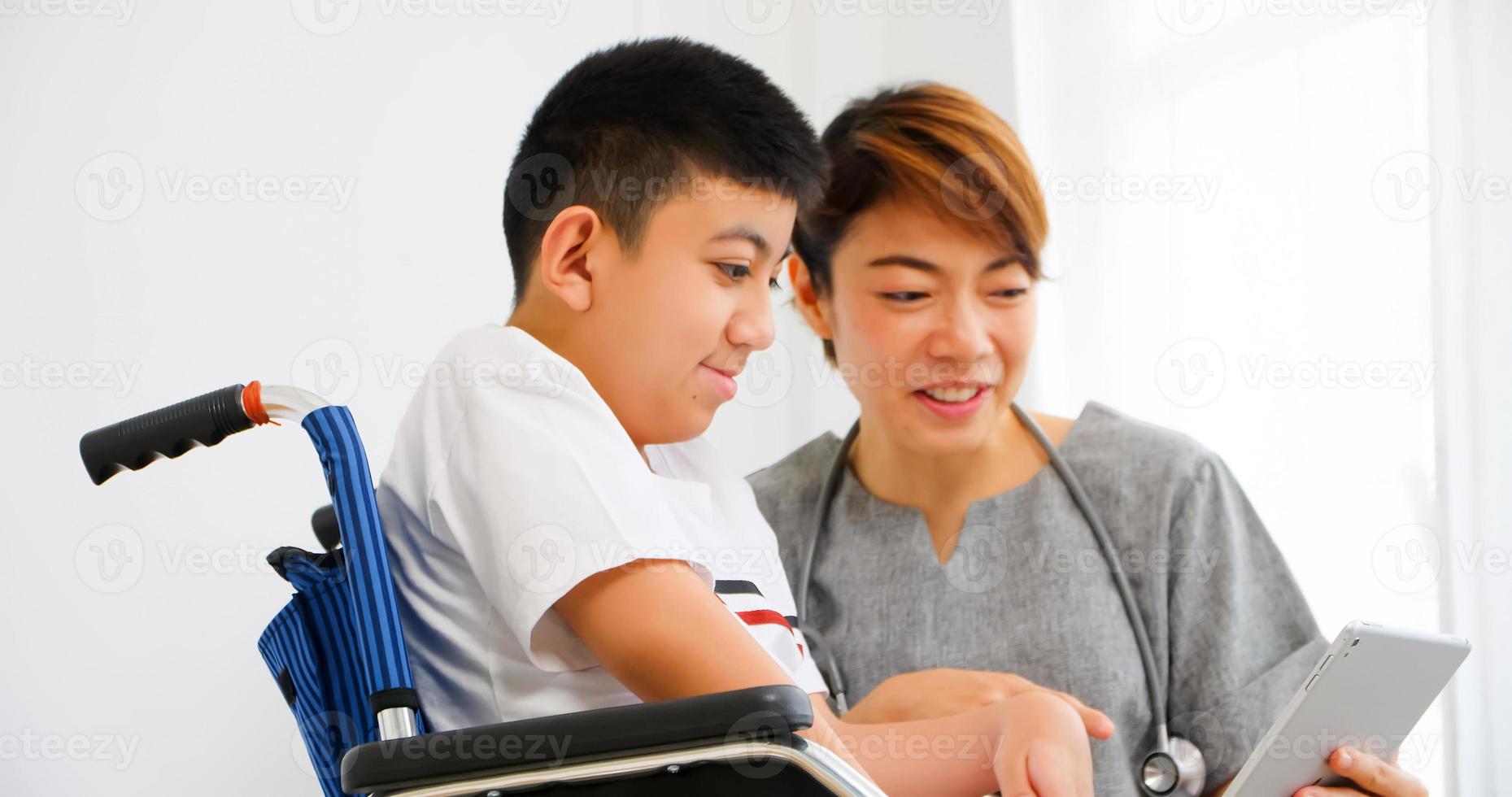 A physical therapist is talking to a disabled boy in a wheelchair. photo