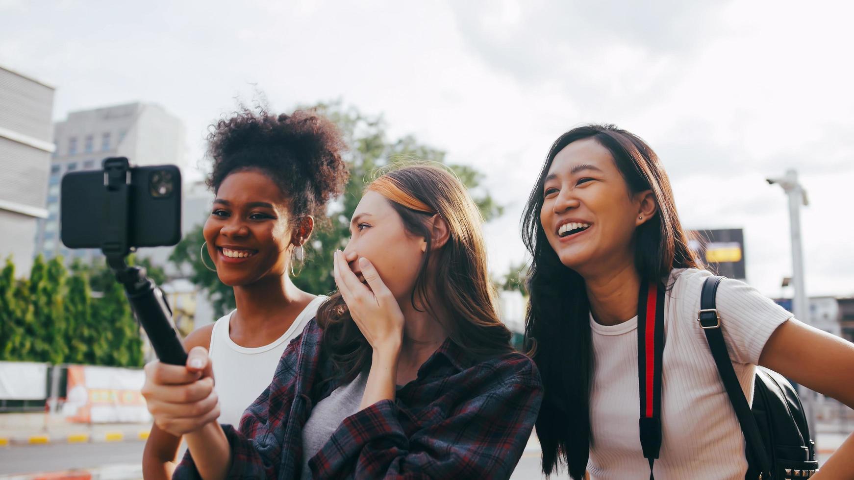 A group of multi-ethnic female friends enjoying the city tour. Young tourists having fun taking pictures together. photo