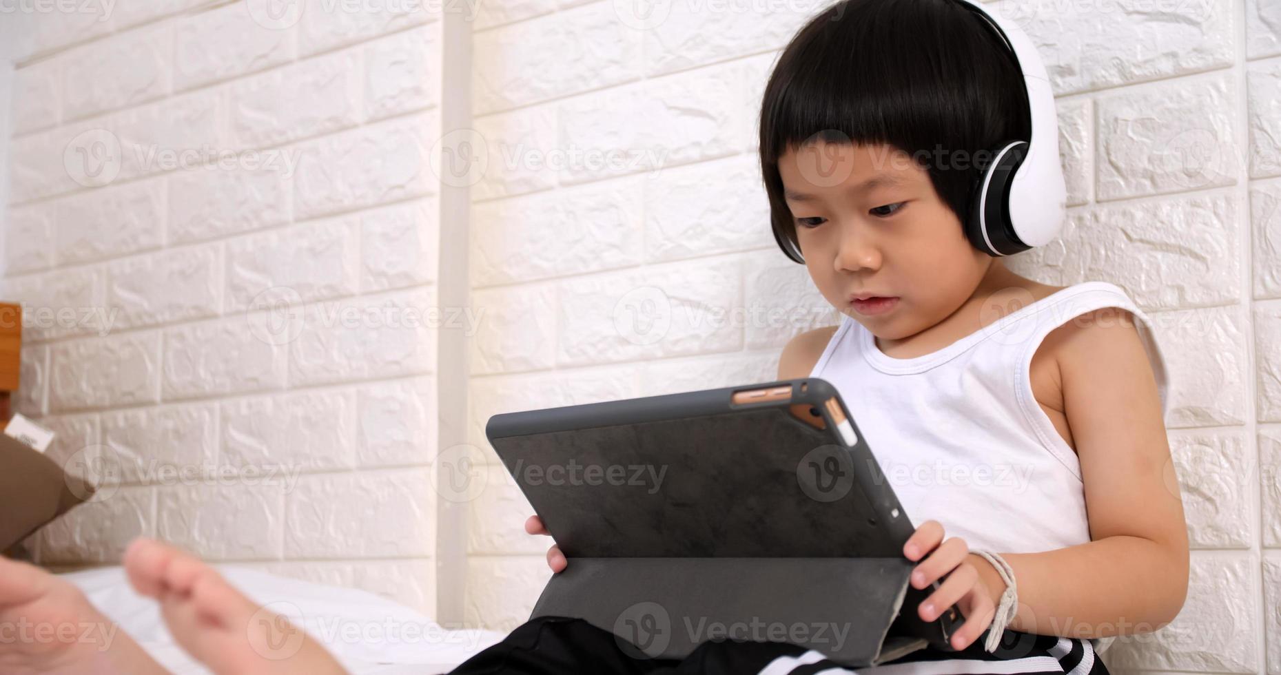 Cute little boy using tablet computer at home. photo