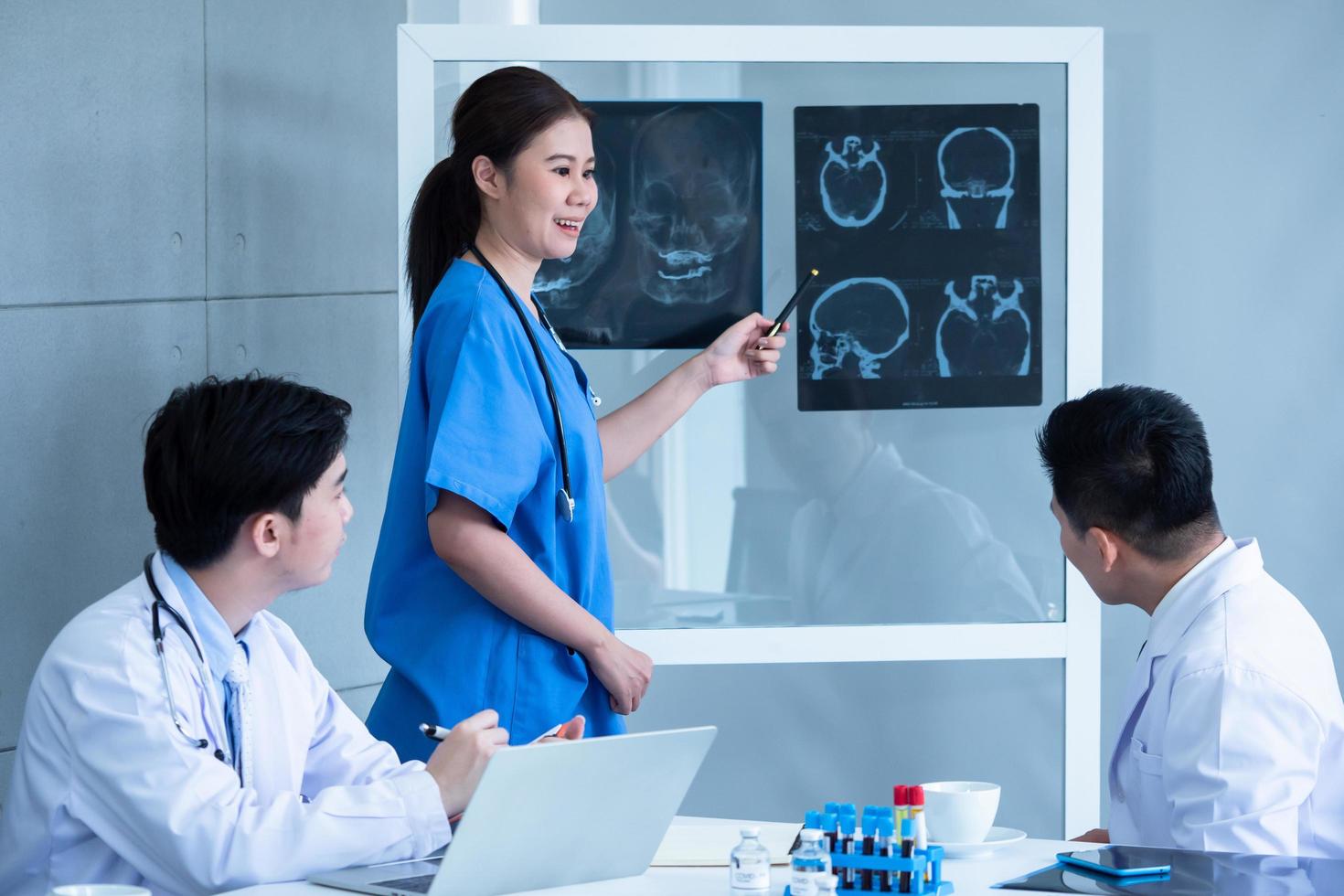 Doctor and medical assistants discussing about diagnosis result on x-ray film. photo