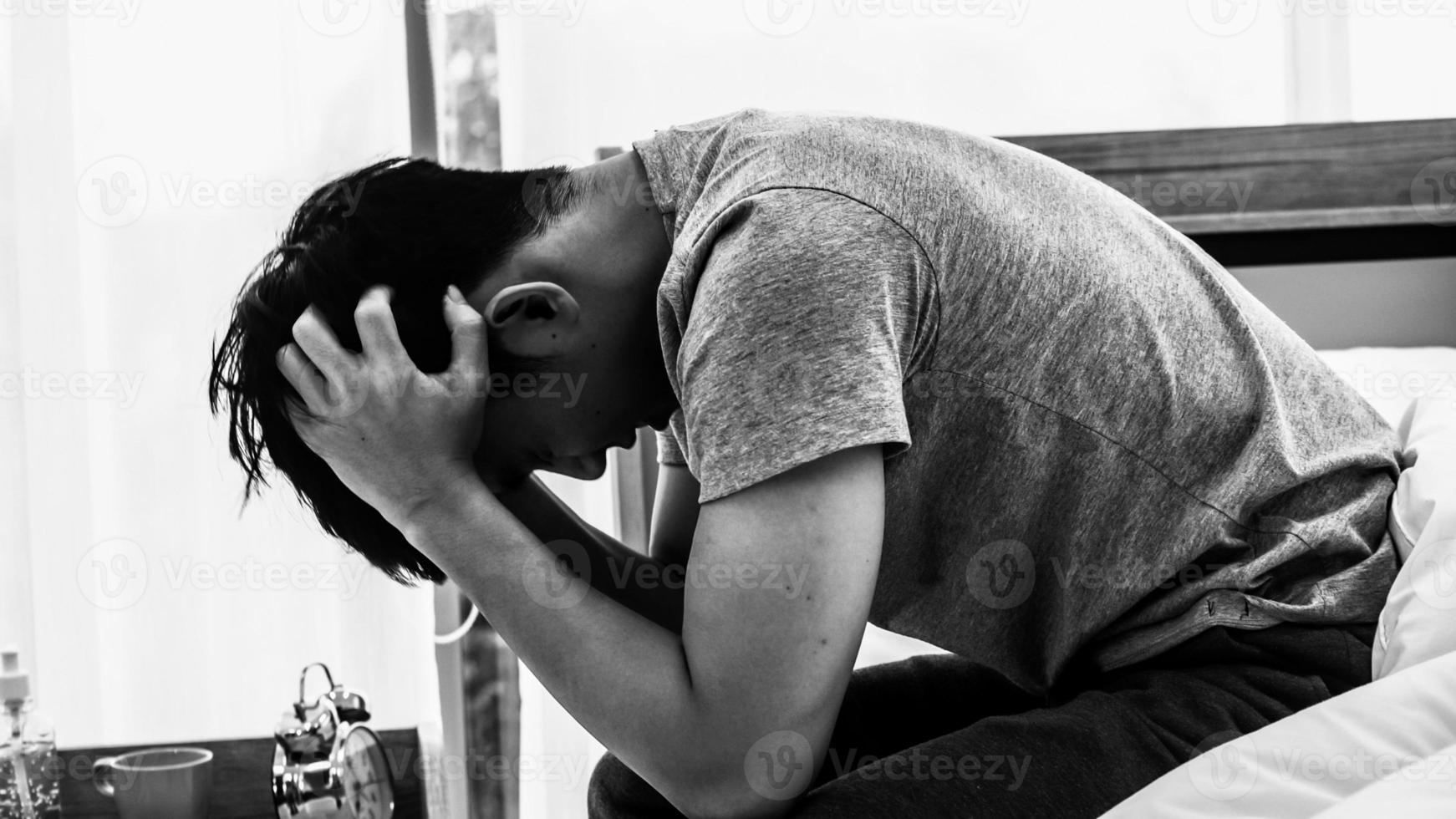 Stressed Asian young man sitting alone on bed. Bad relationship or bankrupt problem and sickness concept. photo