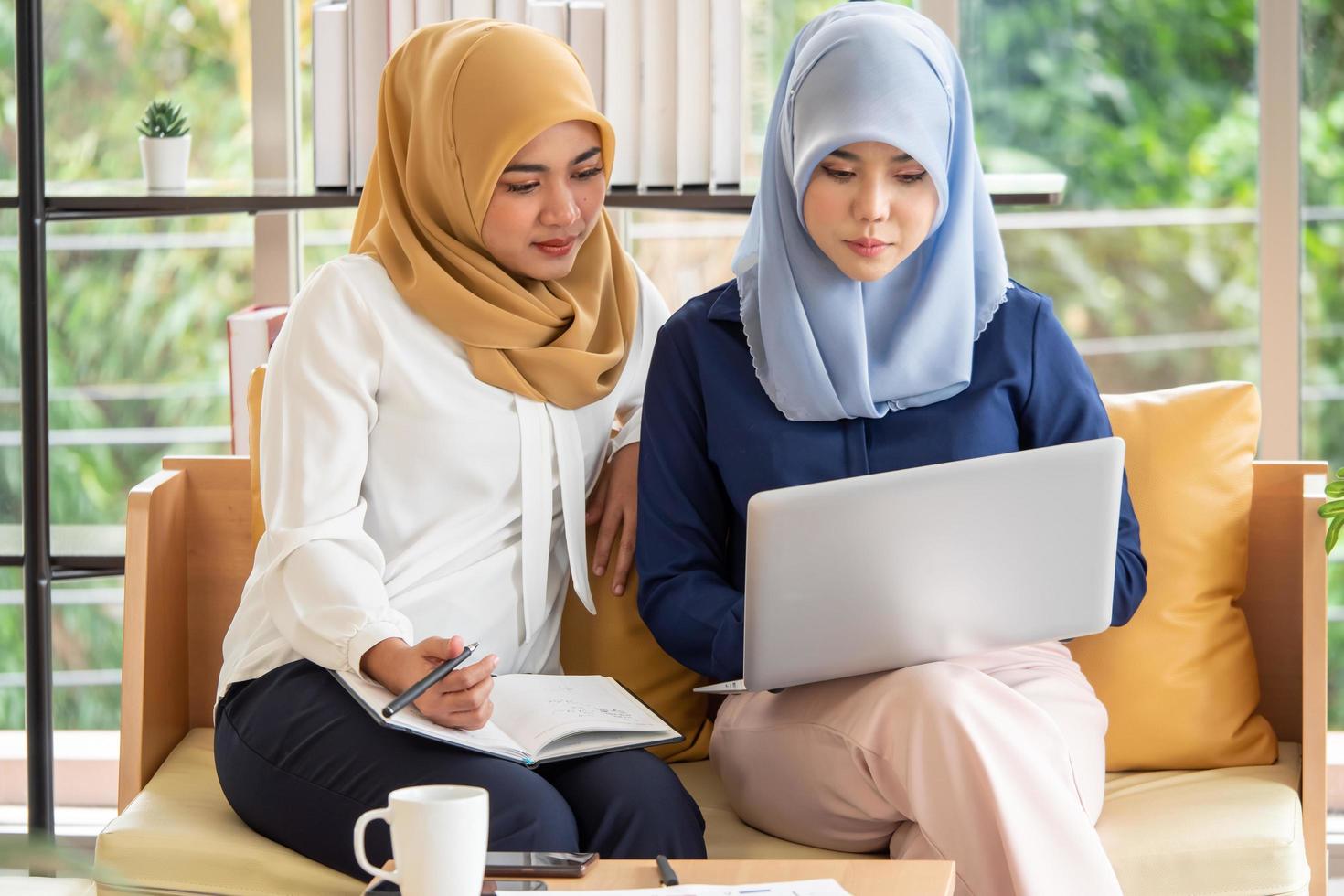 Two young muslim businesswomen discussing a work in the office. photo