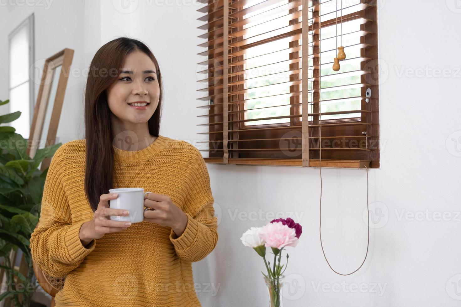 Young Girl Sitting In Modern Chair, Enjoying Coffee In Front Of Window, Side View photo