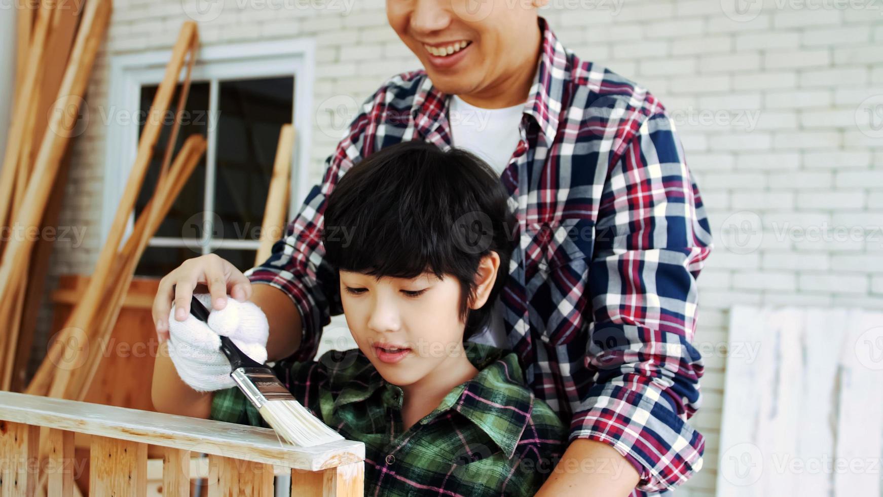 Young male carpenter teaching his son how to work with wood in workshop. photo