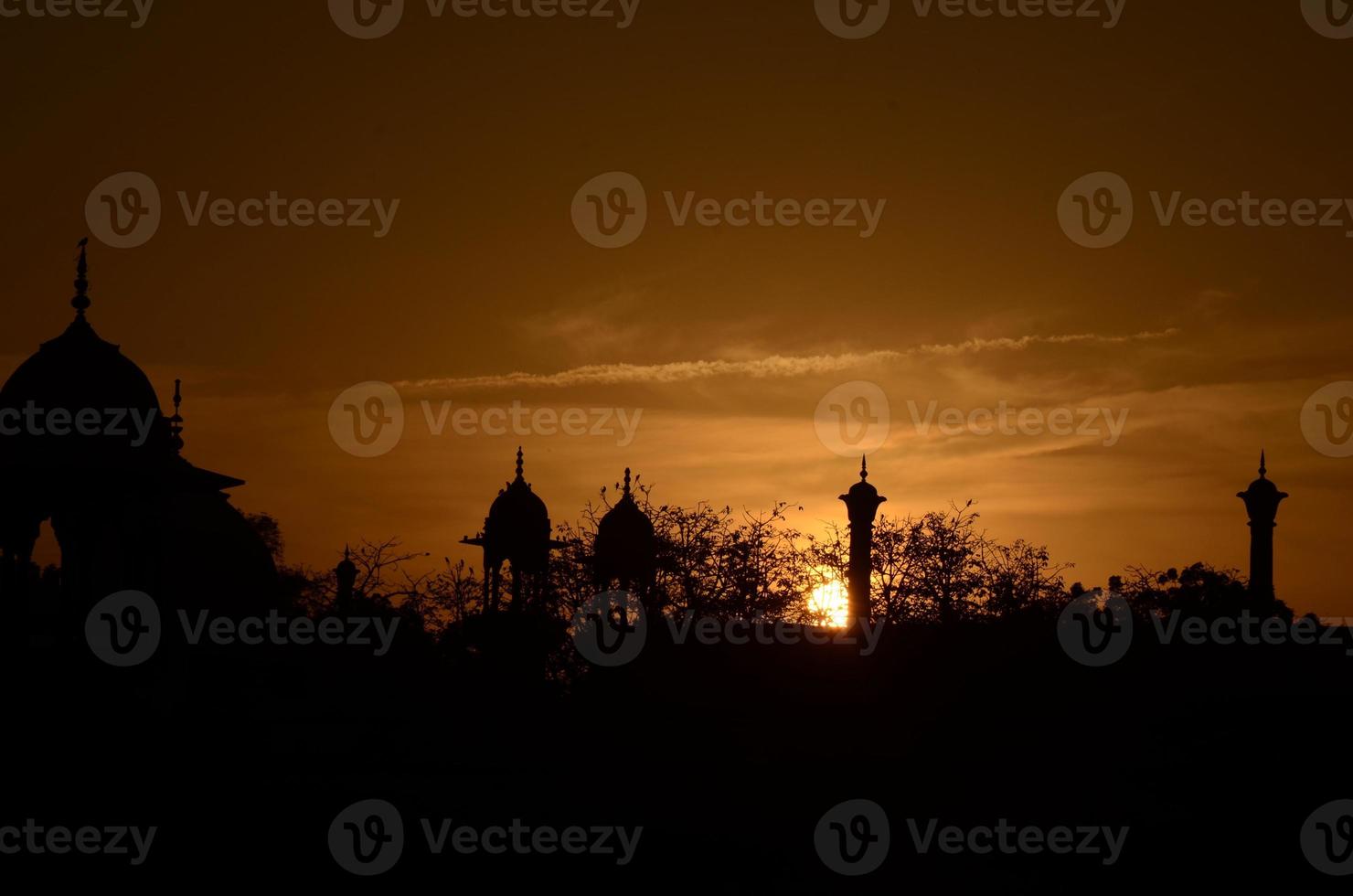 hermosa puesta de sol contra los rayos dorados de un sol poniente mientras los pájaros regresan a sus nidos pacíficos. la arquitectura mogol se destaca recortada contra el cielo dorado. foto