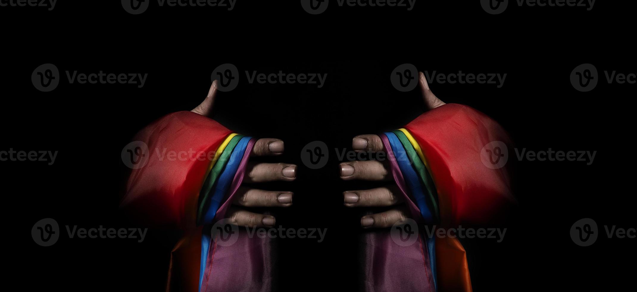 LGBTQ pride flag on black background. Lgbt rainbow flag in gay hand. photo