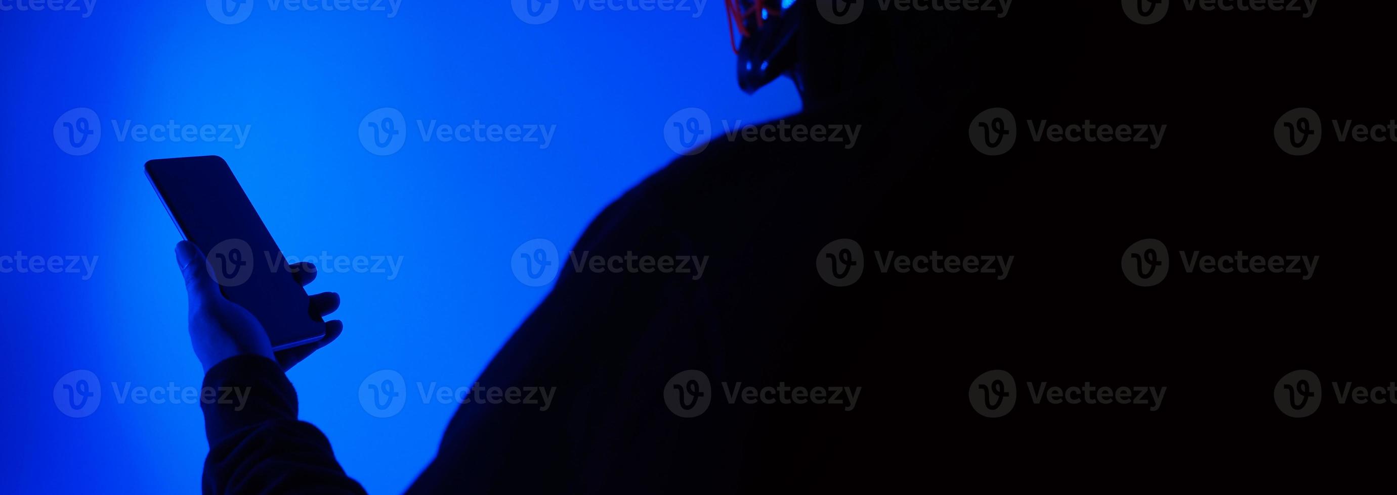 Anonymous hacker and face mask with smartphone in hand. photo