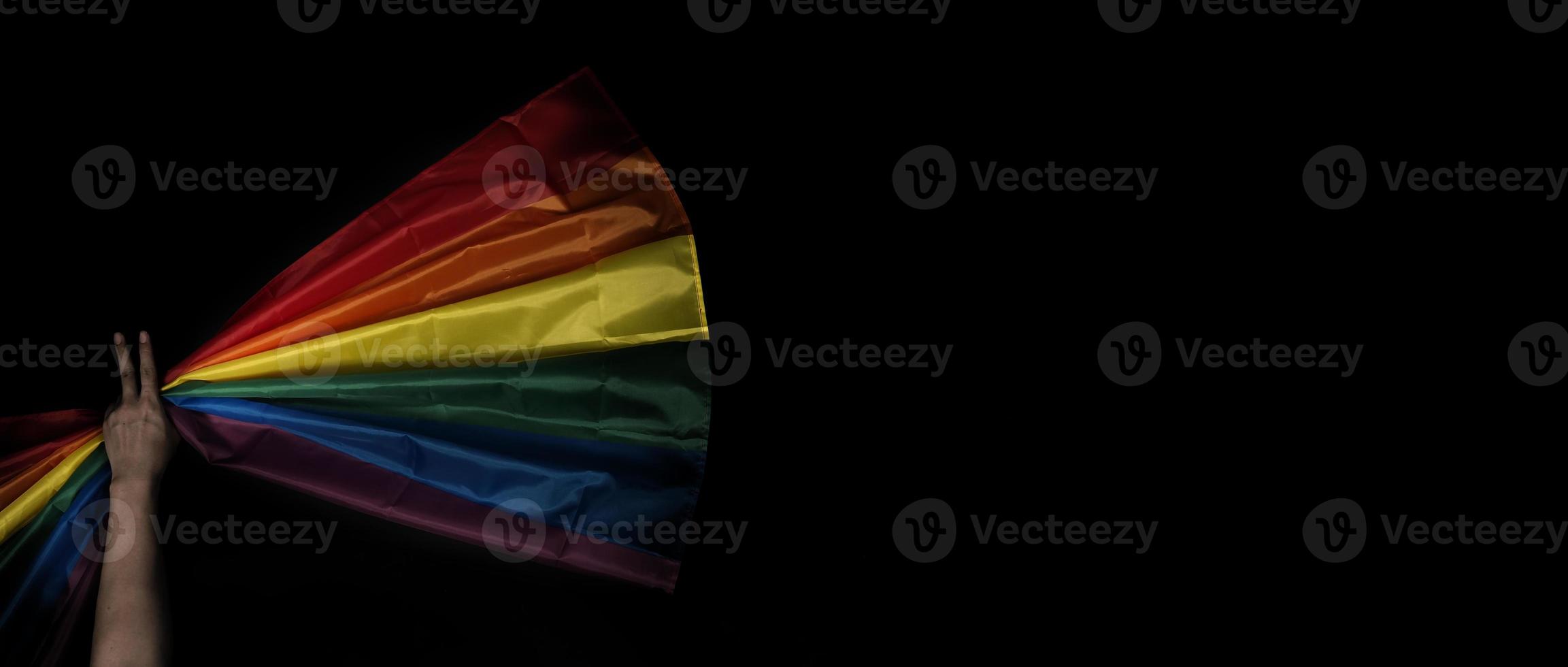 LGBTQ pride flag on black background. Lgbt rainbow flag in gay hand. photo