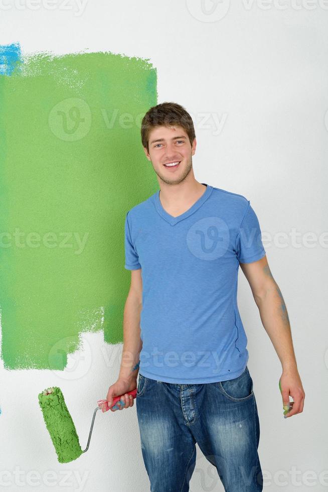 handsome young man paint white wall in color photo