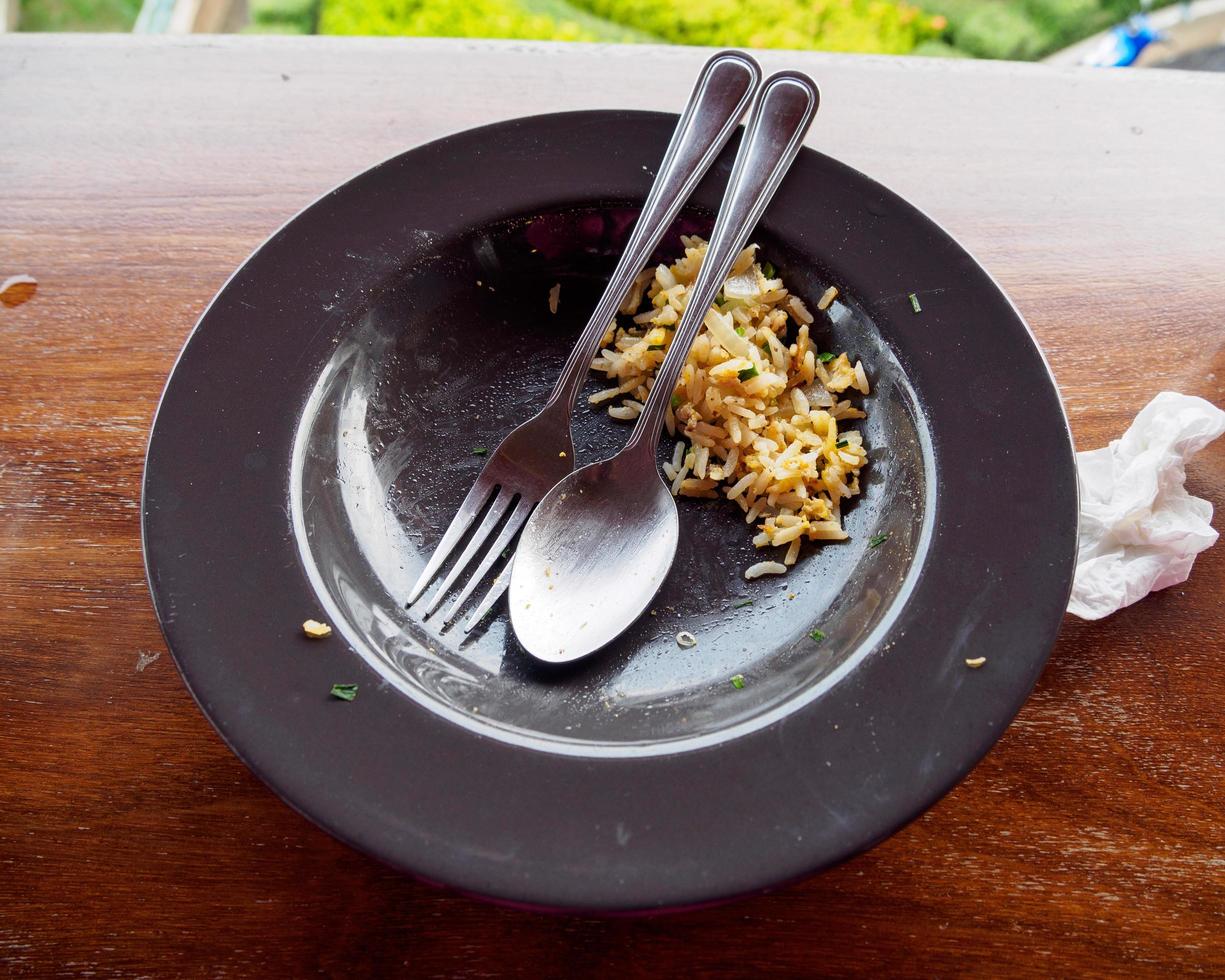 vista frontal de platos de comida morados y cucharas de práctica plateadas, así como servilletas blancas y restos de arroz estaban cuidadosamente colocados. después de almorzar dentro de un restaurante foto