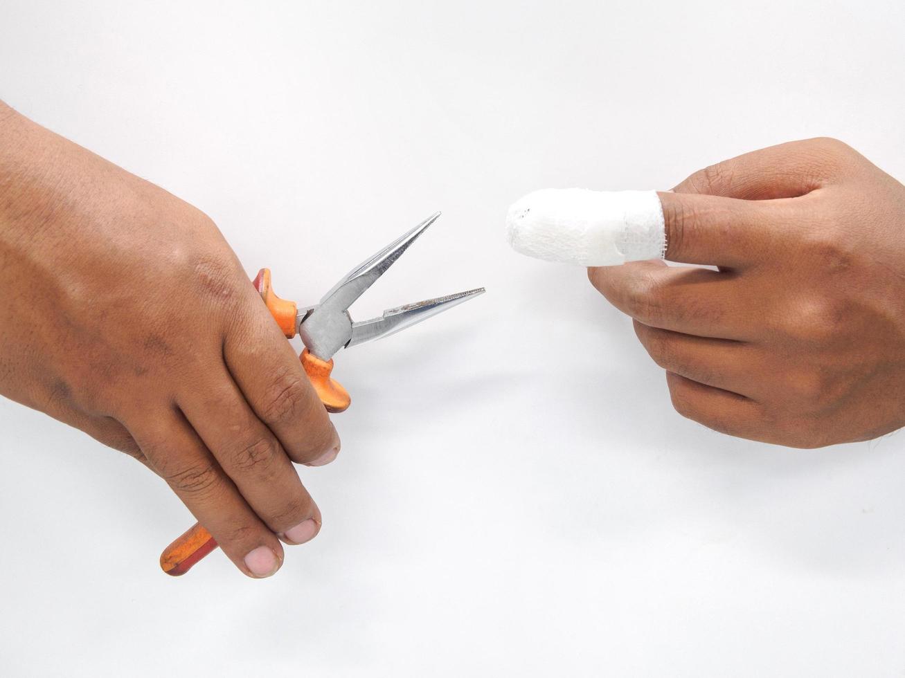 Close-up hand  Asian male technician holding a tool is in danger. And injury to the fingers from work In industrial systems With first aid With bandage at the hospital on a white background. photo