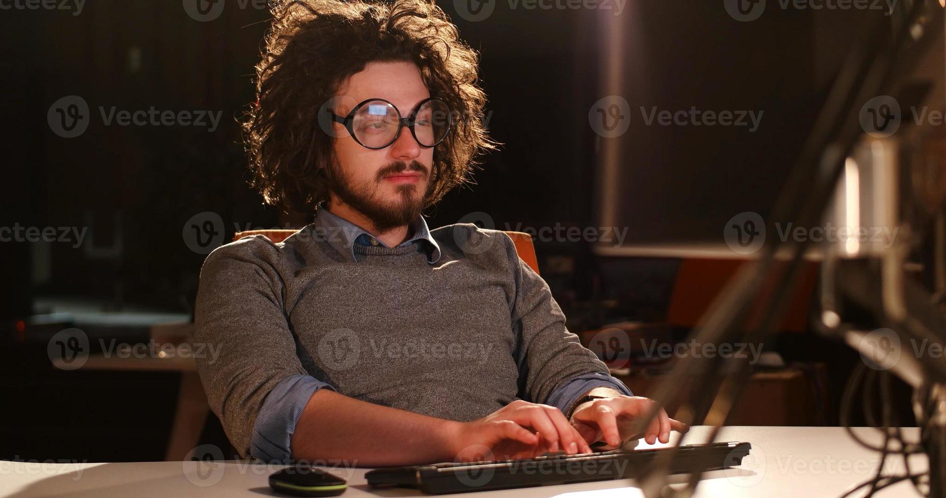 man working on computer in dark office photo