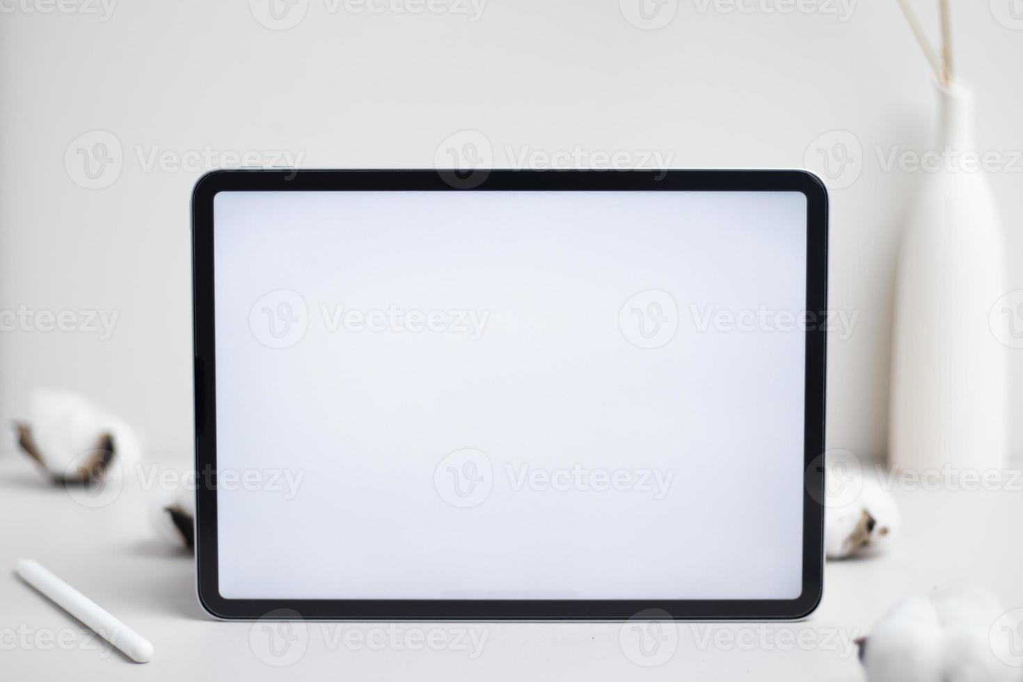 Tablet empty white screen with pencil and cotton flower on white background mockup for design photo