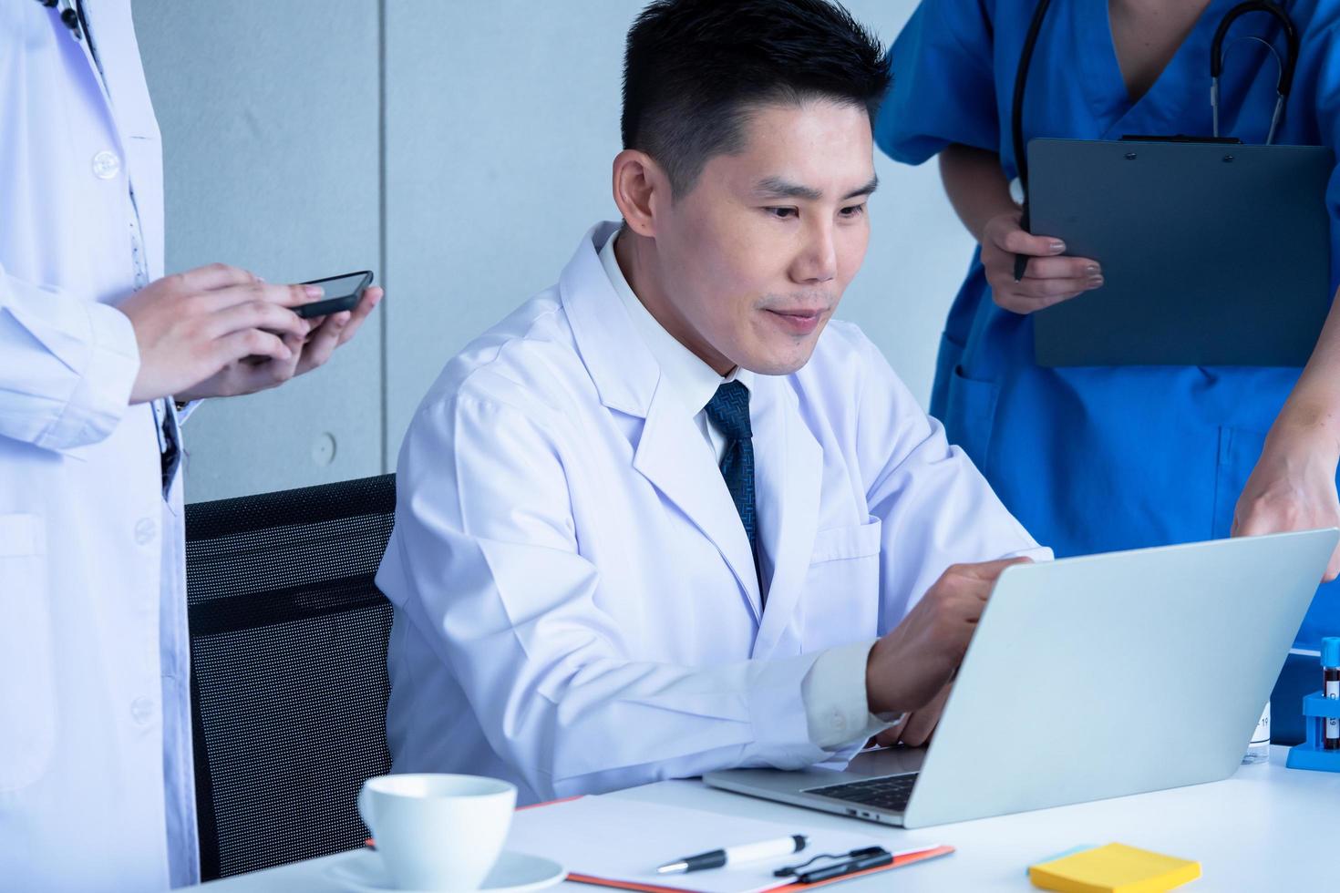 Doctor and medical assistants discussing about diagnosis result on laptop. photo