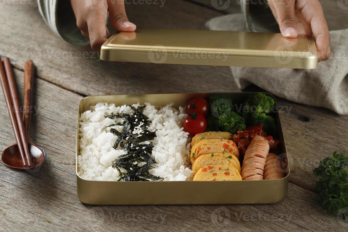 mano femenina preparando dosirak o caja bento coreana, servida en una  lonchera de metal dorado para mantener la comida caliente. 11273335 Foto de  stock en Vecteezy