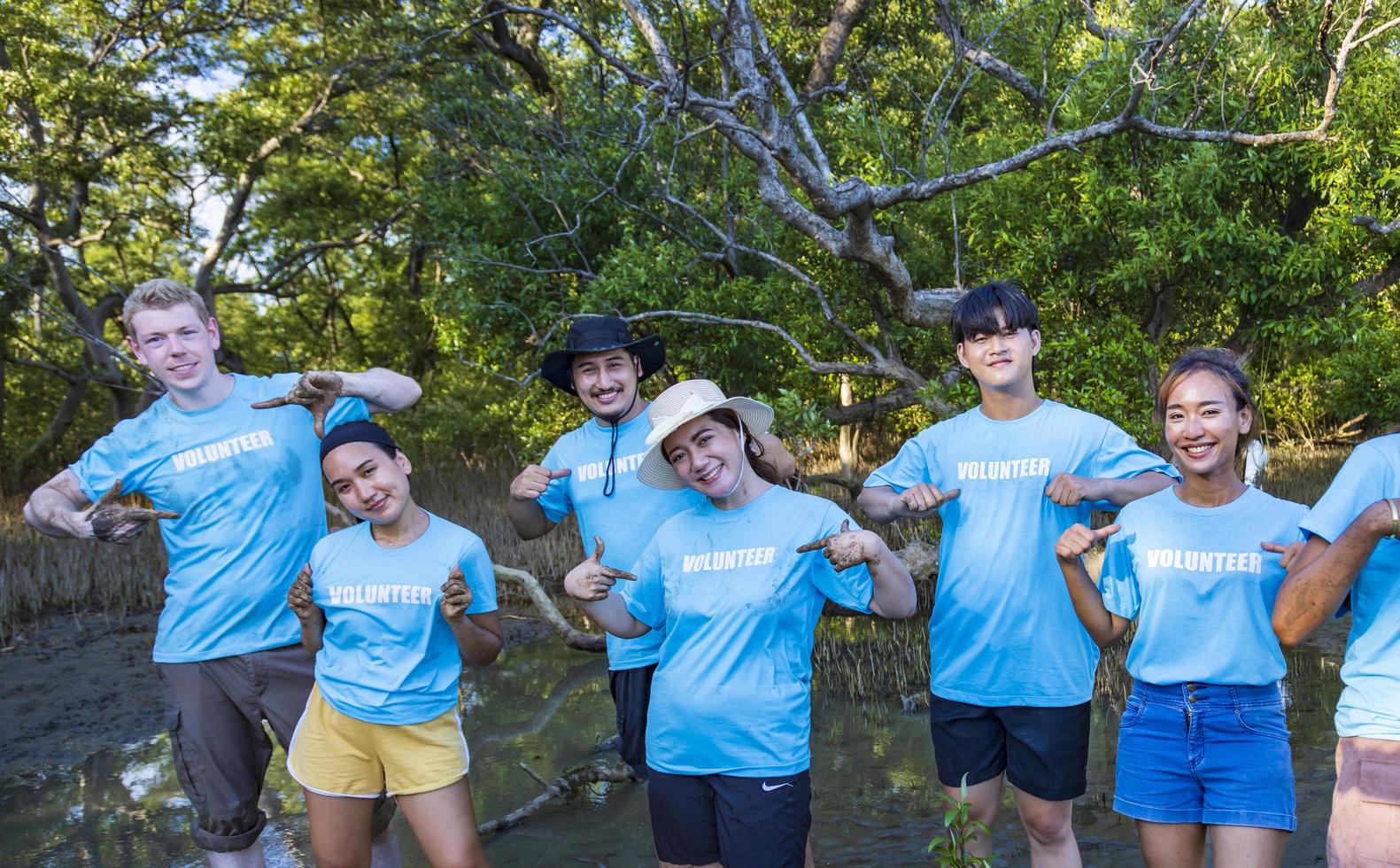 Team of young and diversity volunteer worker group enjoy charitable social work outdoor in mangrove planting project wearing blue t-shirt photo