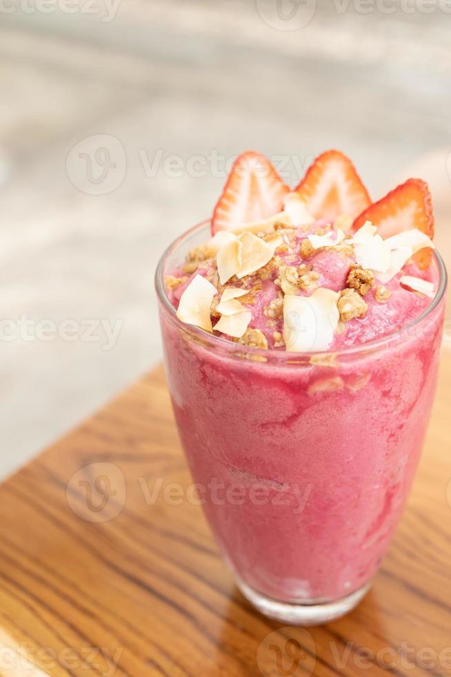 batido de fresa con fresas en vidrio sobre una mesa de madera foto