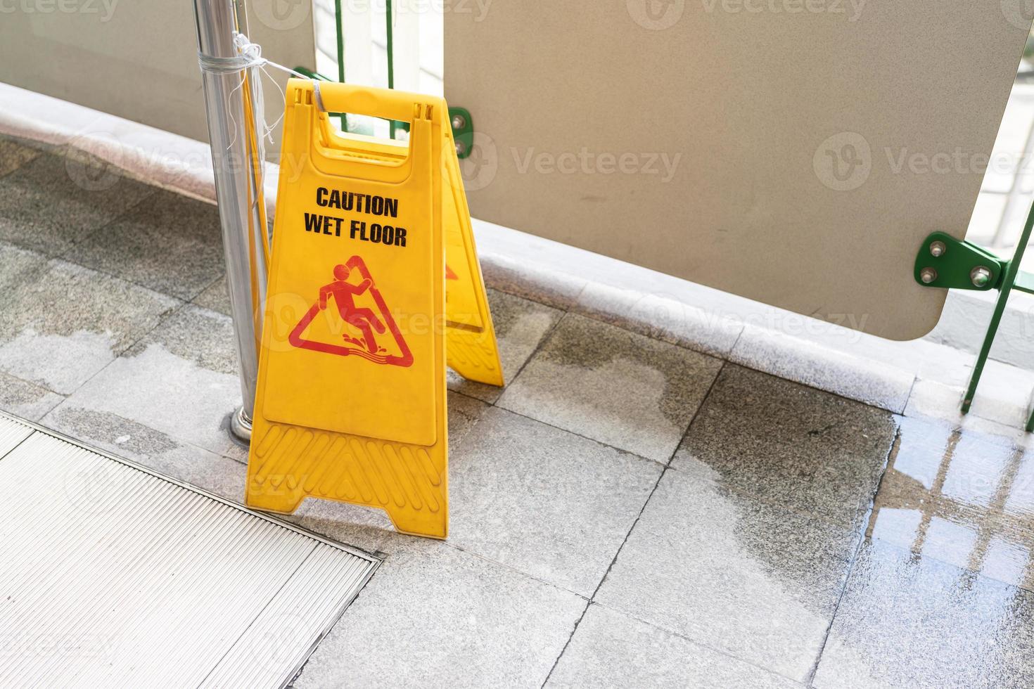 Yellow Caution slippery wet floor sign on the wet ground photo