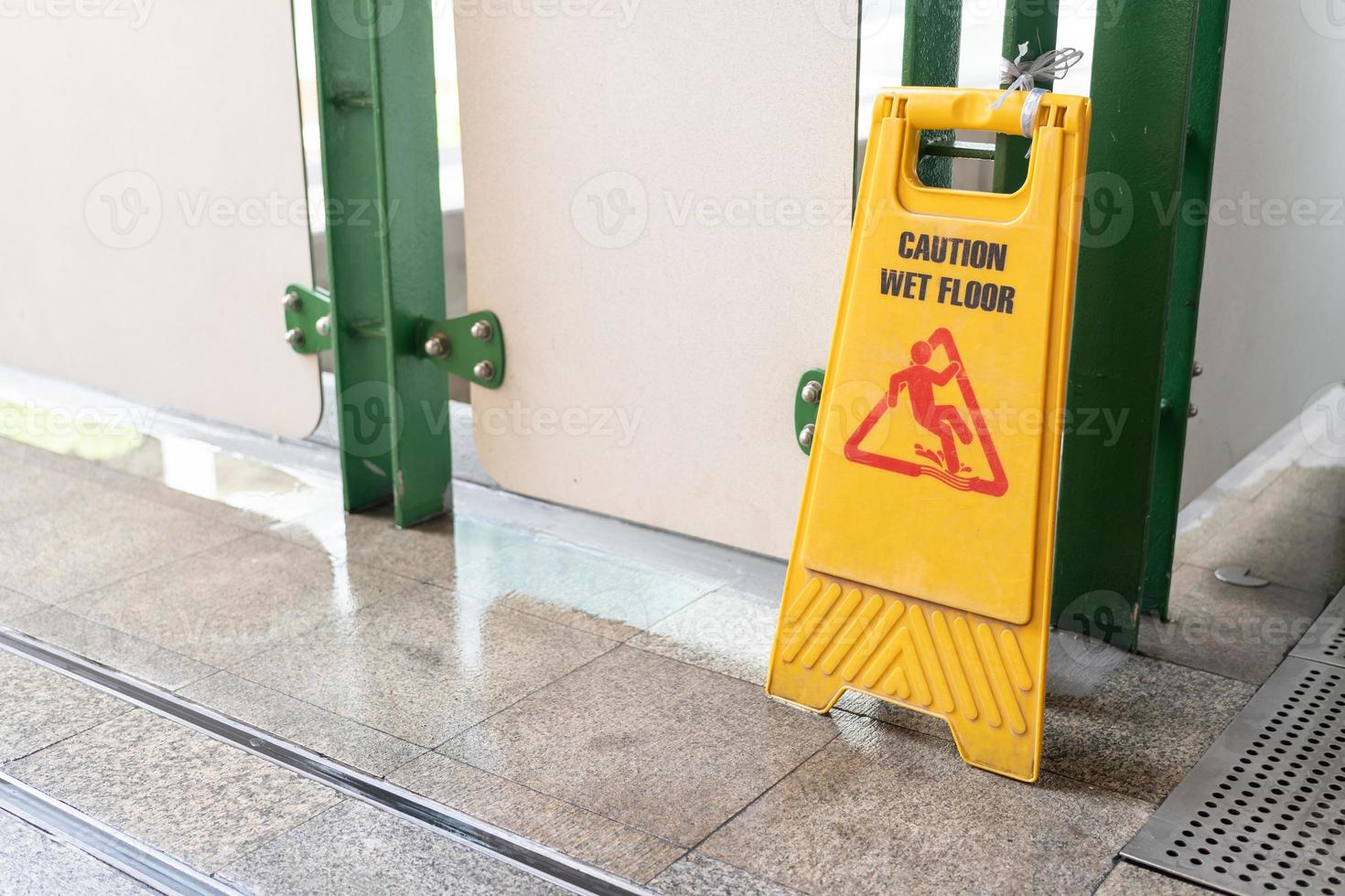 Yellow Caution slippery wet floor sign on the wet ground photo