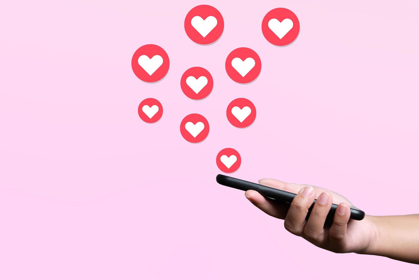 People use mobile phone sending hearts. Love and connection concept using telephone application on pink background. photo