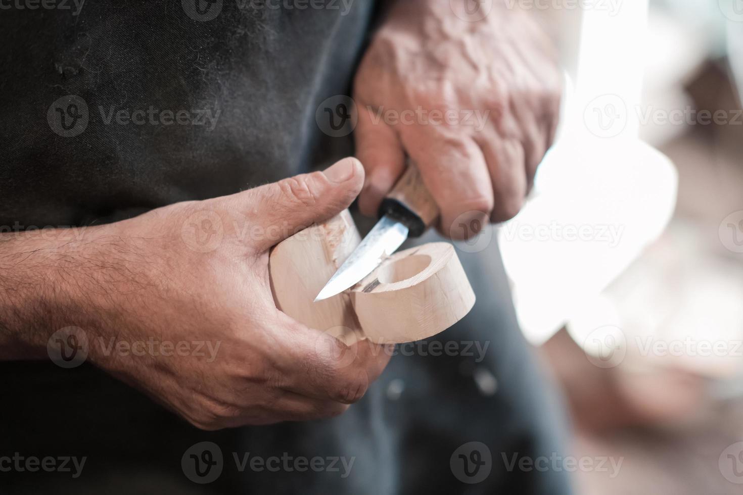 Hands carving cup from wood, working with chisel close up. Wooden workshop. Process of making wooden kitchenware photo