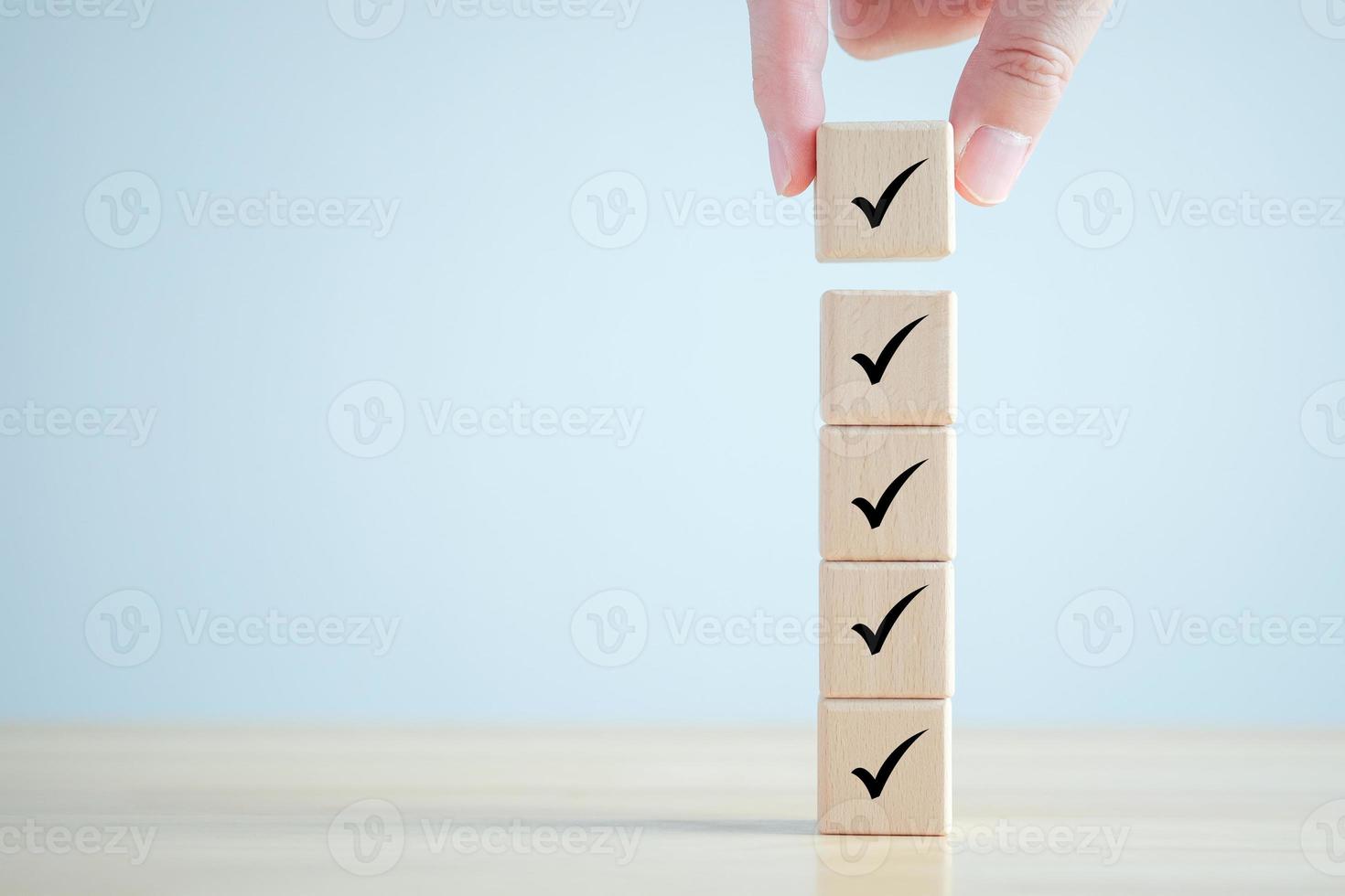 Checklist, Task list, Survey and assessment. Quality Control. Goals achievement and business success. Hand holding Check mark on wooden blocks for complete check list. photo